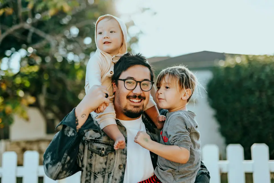 Familia hispana feliz: un padre latino con sus hijos, protegidos con su seguro en USA