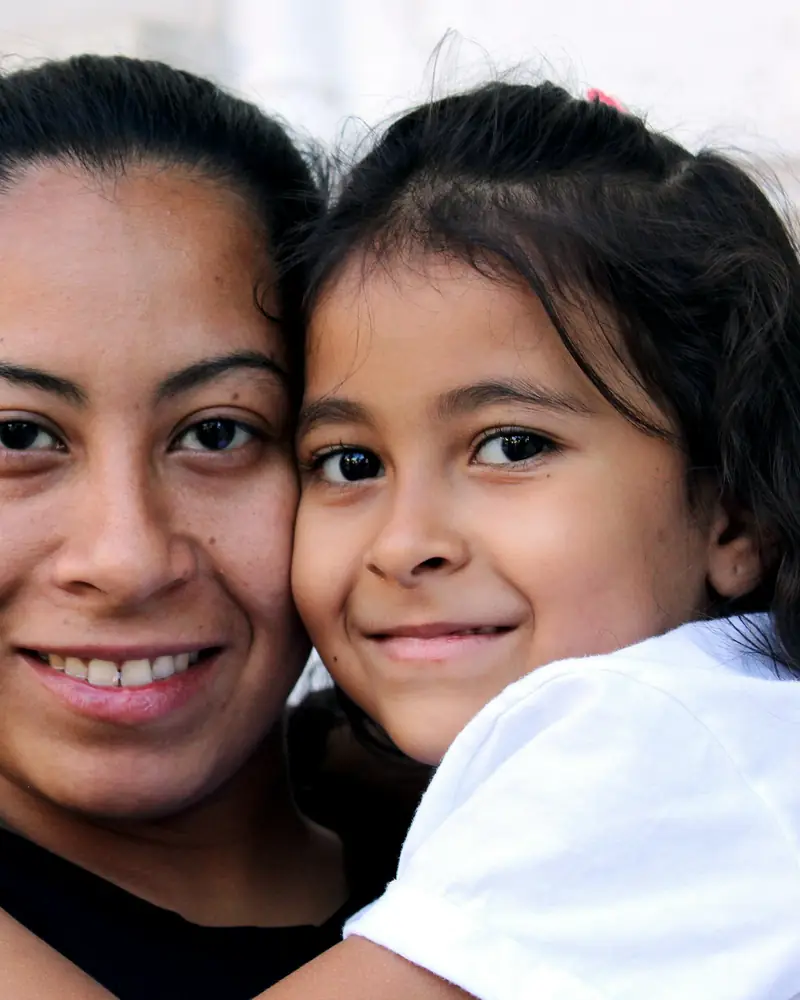 Madre latina abrazando a su hija, tranquilas con la protección de su seguro familiar