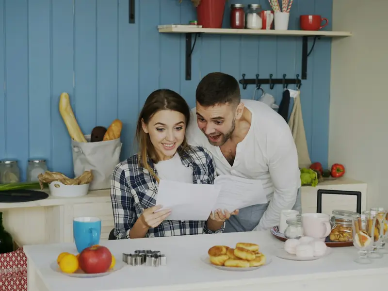 Pareja hispana revisando los documentos de su seguro médico en la cocina de su casa
